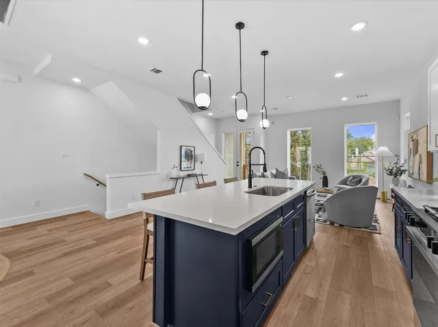 a kitchen with a stove a sink a center island and wooden floor