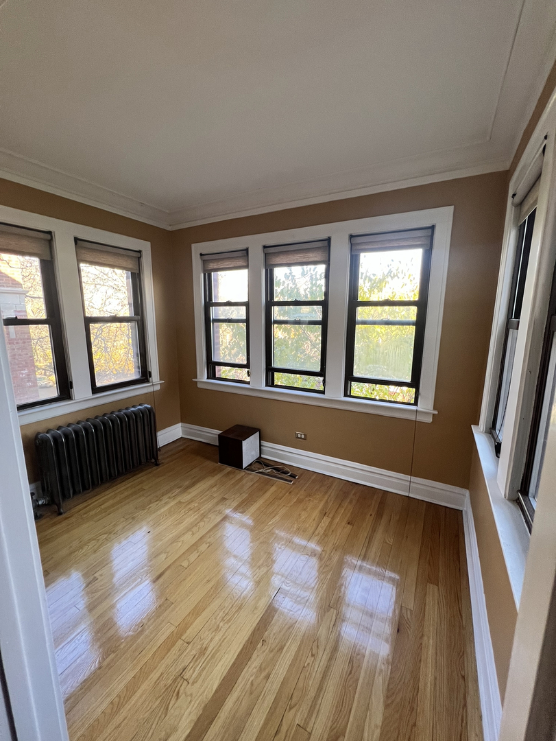 6830 South Paxton Avenue, Unit 3A Chicago, IL 60649 - Photo 4 of 8 a view of an empty room with wooden floor and a window