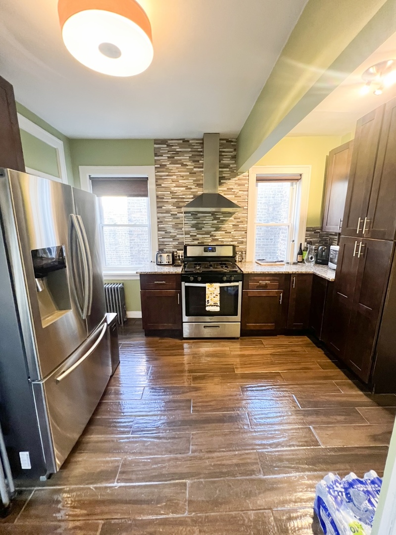 6830 South Paxton Avenue, Unit 3A Chicago, IL 60649 - Photo 8 of 8 a view of a kitchen with wooden floor and stainless steel appliances