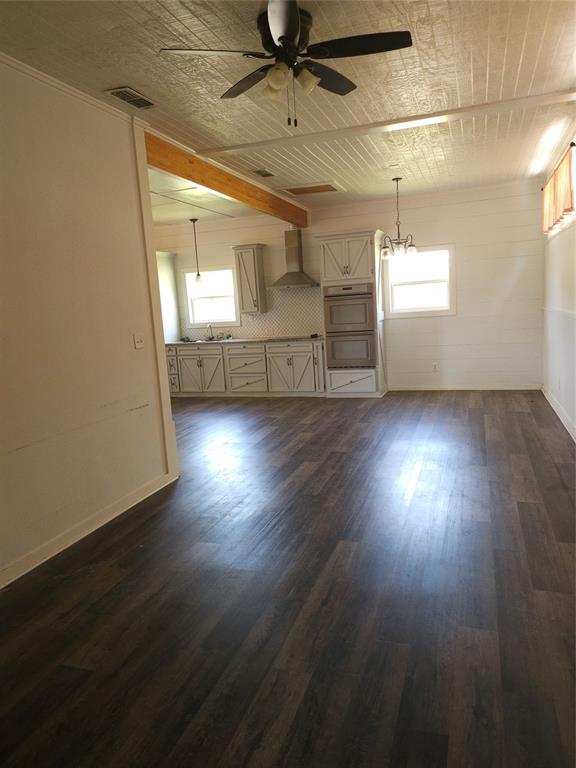 an empty room with wooden floor chandelier and windows