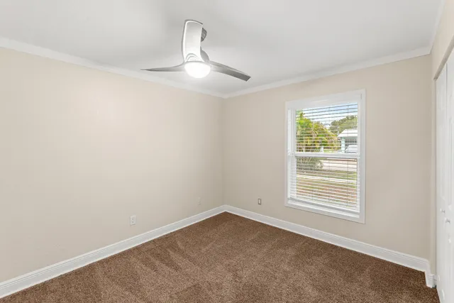 an empty room with a ceiling fan and a window
