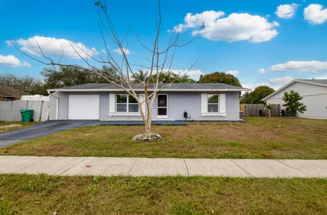 a white house with a big yard and swimming pool