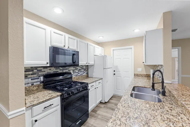 a kitchen with granite countertop a sink stove and cabinets