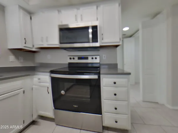 a kitchen with stainless steel appliances granite countertop white cabinets and a stove top oven