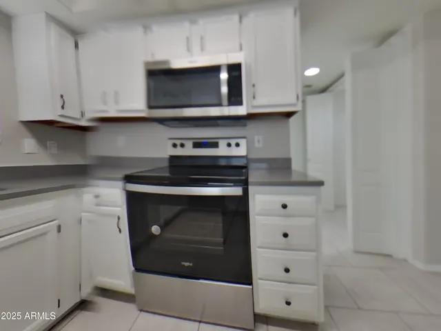 a kitchen with stainless steel appliances granite countertop white cabinets and a stove top oven