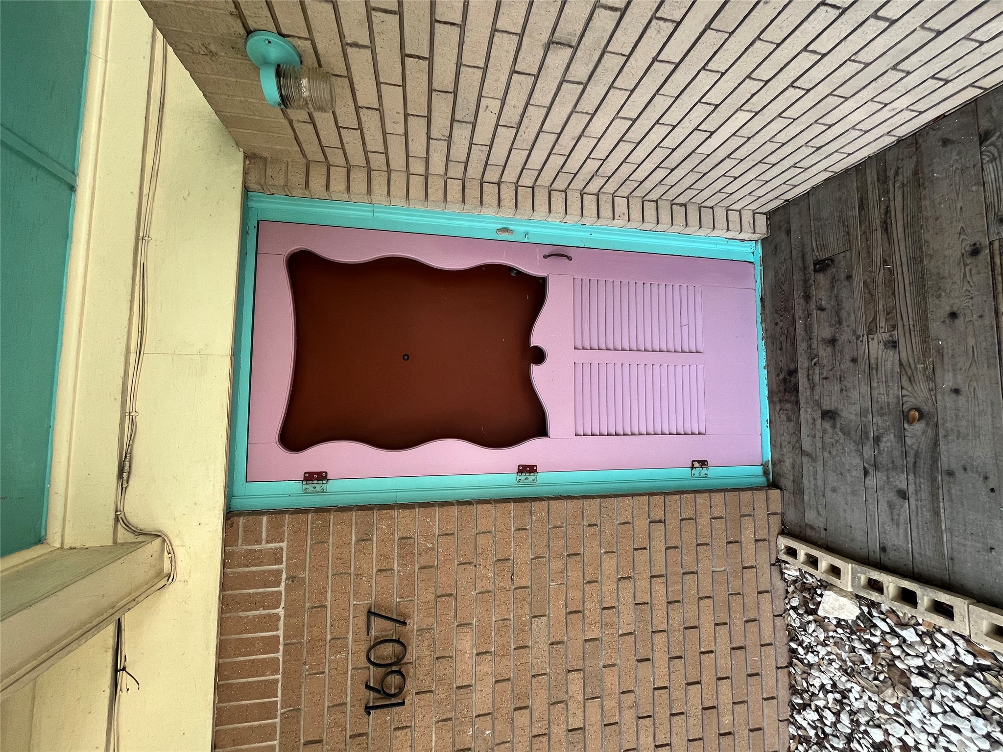 1607 Lightsey Road, Unit A Austin, TX 78704 - Photo 4 of 17 Brick exterior with a vibrant pink and teal entry door, featuring louvered detailing and a unique top panel design