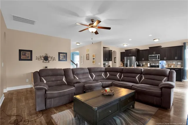 a living room with furniture kitchen view and a chandelier
