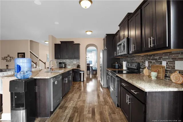 a kitchen with stainless steel appliances granite countertop a sink a stove and a wooden floors