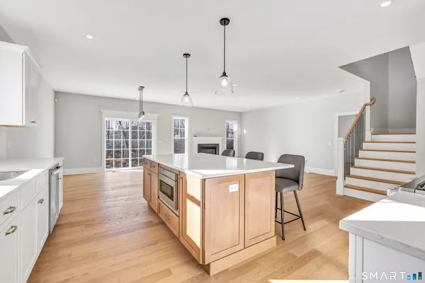 a large white kitchen with a large counter top a sink a stove and wooden floors