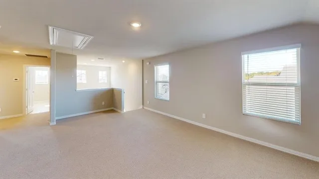 a view of an empty room with a window and a kitchen