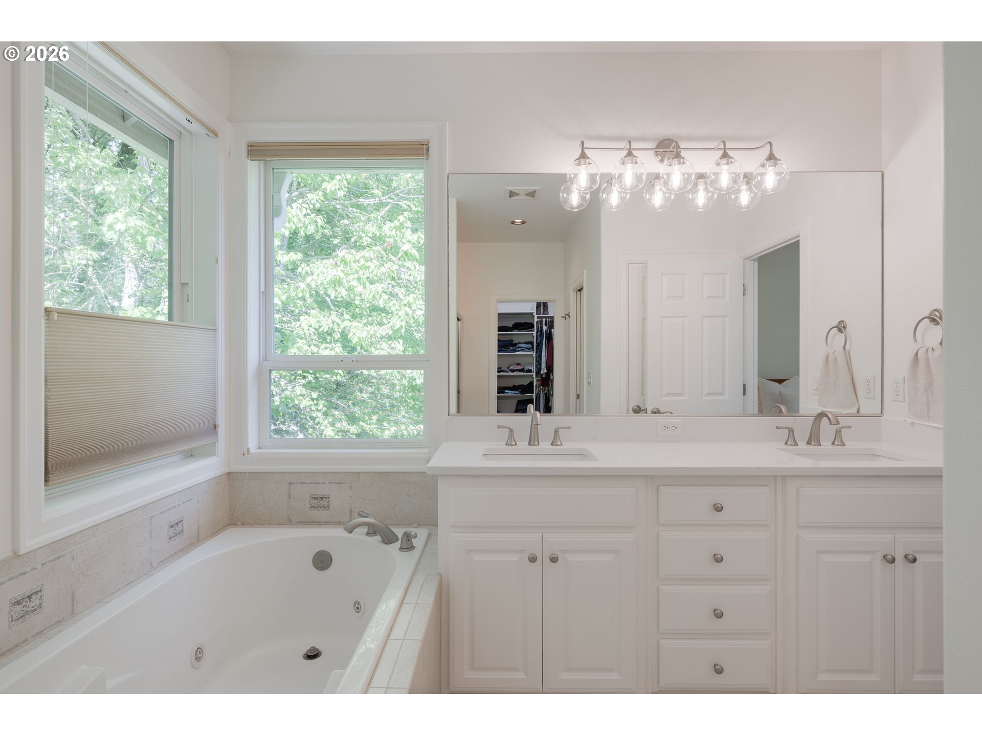 2097 Southwest Nancy Drive Gresham, OR 97080 - Photo 27 of 46 a bathroom with a tub a double vanity sink a large mirror and a bathtub next to a window