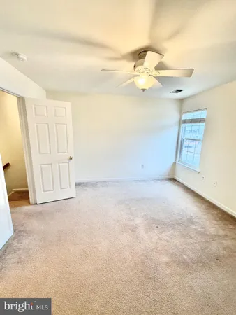 an empty room with windows and fan