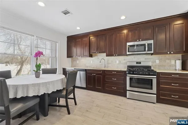 a kitchen with kitchen island granite countertop wooden cabinets dining table and stainless steel appliances