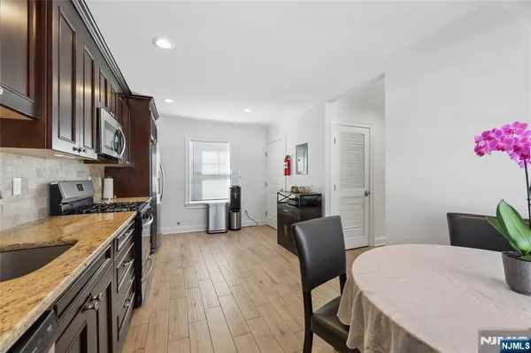 a kitchen with stainless steel appliances granite countertop a kitchen island hardwood floor sink stove dining table and chairs