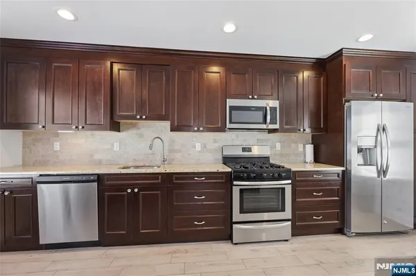 a kitchen with granite countertop wooden cabinets and stainless steel appliances