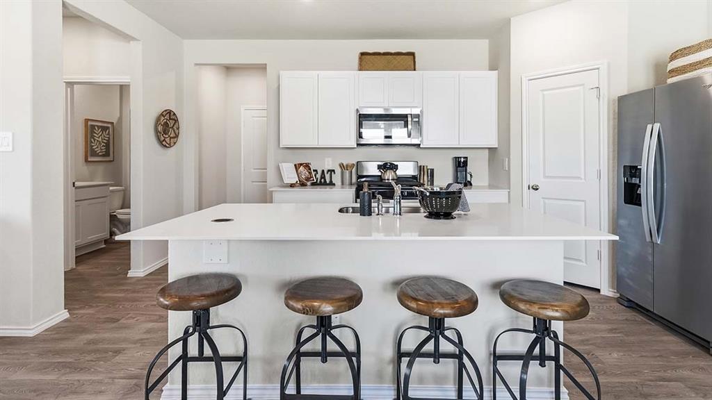 226 Pheasant Run Road Terrell, TX 75160 - Photo 20 of 36 Kitchen featuring a large island, white cabinetry, stainless steel appliances, and wood-finish flooring