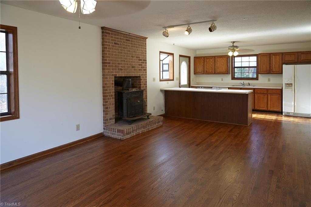 544 Neal Road Madison, NC 27025 - Photo 6 of 28 Open living/dining area with a wood stove and newly refinished hardwood floors. Heat pump that services the main level and the basement was replaced in 2012.