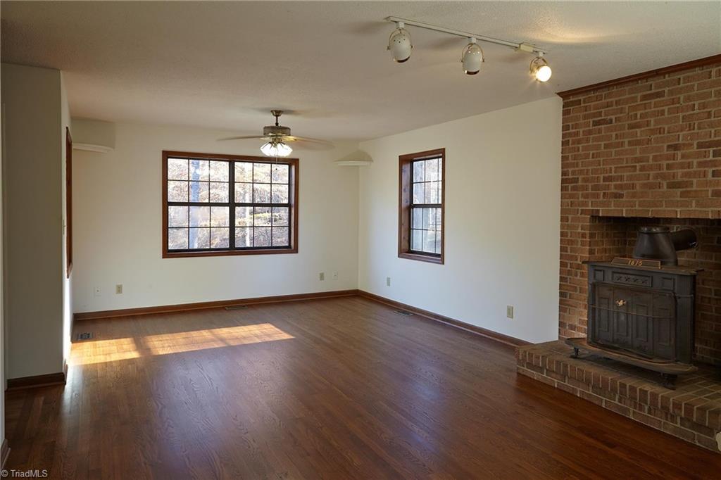 544 Neal Road Madison, NC 27025 - Photo 10 of 28 Living and dining area with wood stove. Note the 6" deep window sills and the newly refinished hardwood floors.