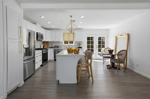 a living room with stainless steel appliances furniture a dining table and chairs