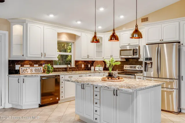 a kitchen with kitchen island granite countertop appliances cabinets and a sink