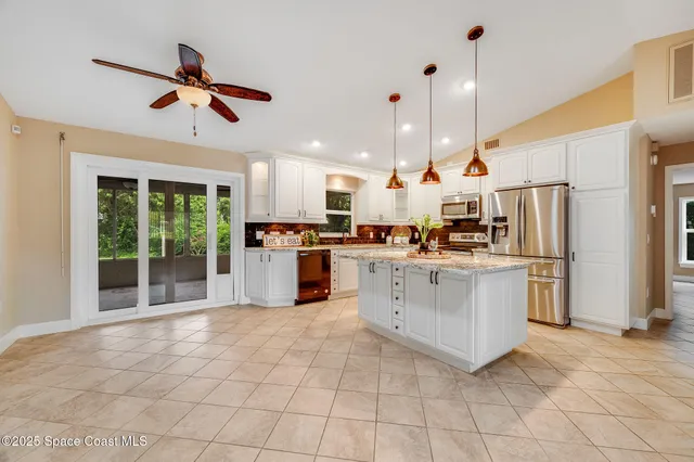 a kitchen with stainless steel appliances kitchen island granite countertop a refrigerator a oven a sink and a stove