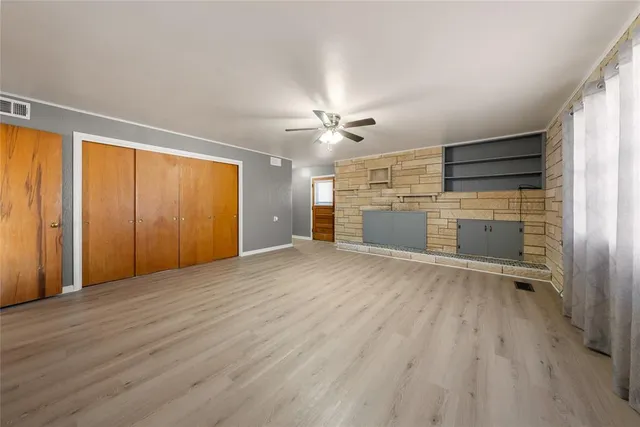 an empty room with wooden floor cabinet and windows