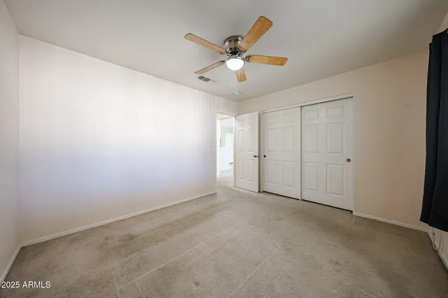 an empty room with closet and ceiling fan