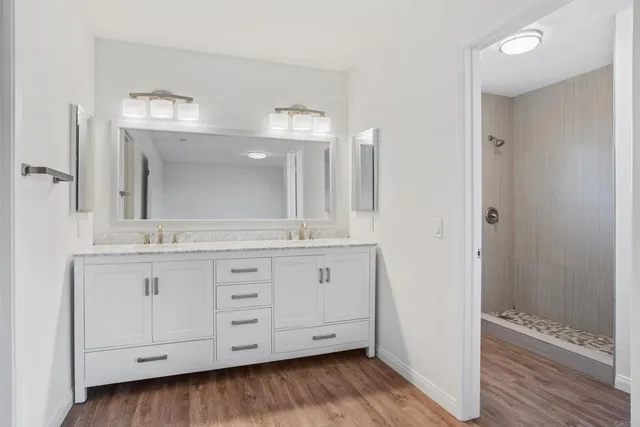 a bathroom with a granite countertop double vanity sink and mirror
