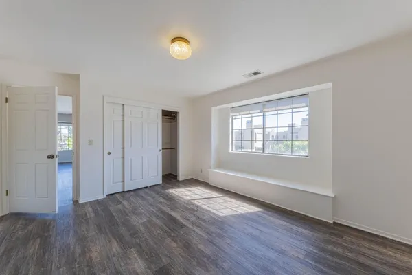 a view of an empty room with window and wooden floor