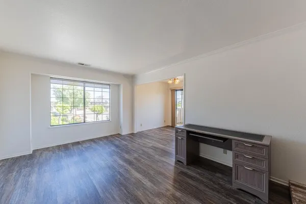 an empty room with wooden floor fireplace and windows