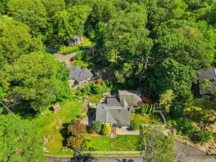 an aerial view of residential house with outdoor space and trees all around