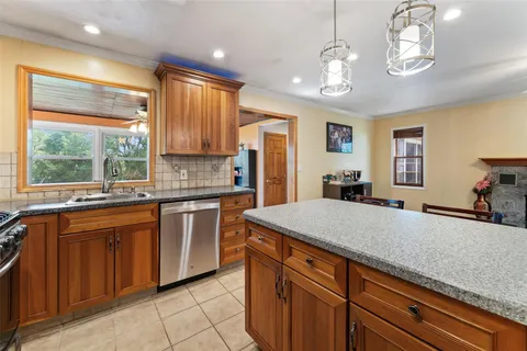 a kitchen with stainless steel appliances granite countertop wooden cabinets a stove a sink a dining table and chairs