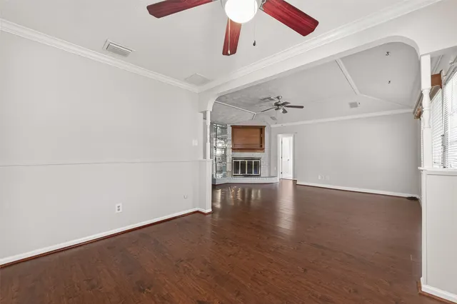 an empty room with wooden floor ceiling fan and windows