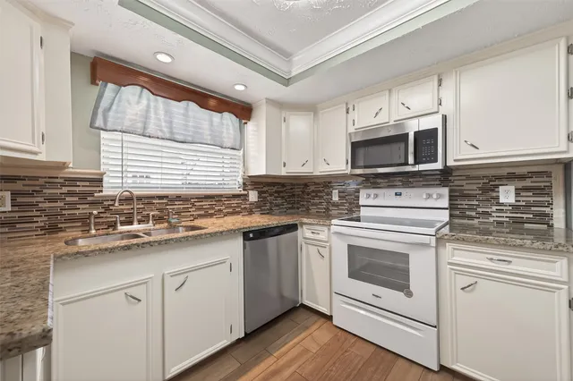 a kitchen with granite countertop white cabinets white stainless steel appliances and a sink