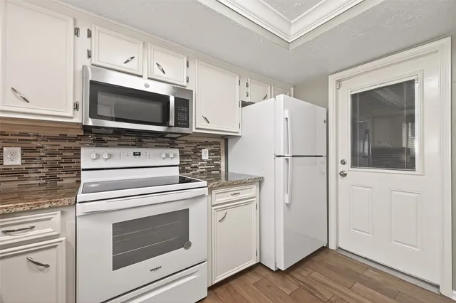 a kitchen with cabinets stainless steel appliances and wooden floor