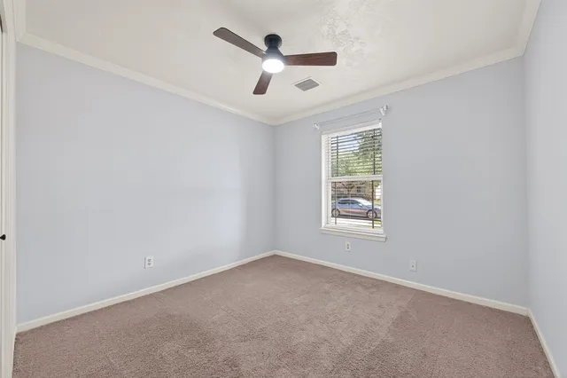 an empty room with ceiling fan and windows