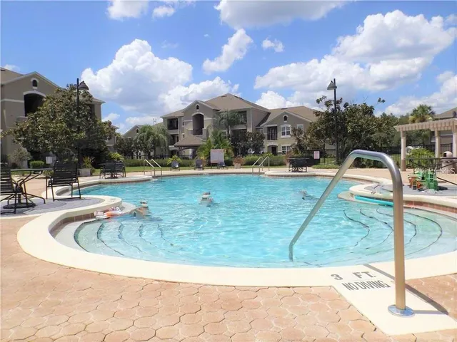 a view of swimming pool with lawn chairs and iron fence