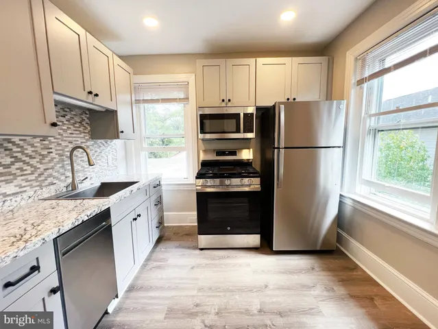 a kitchen with granite countertop a refrigerator stove top oven and sink