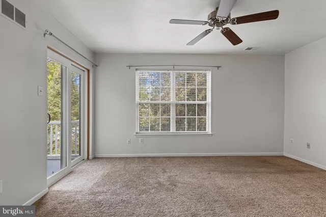 an empty room with chandelier fan and windows
