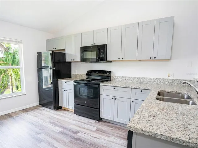 a kitchen with white cabinets and black appliances