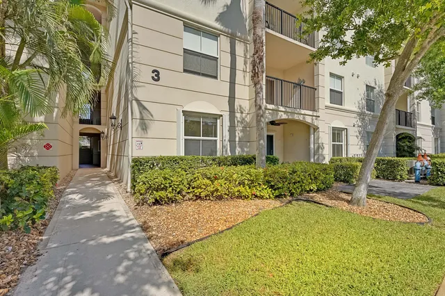 a view of a white house with a large trees