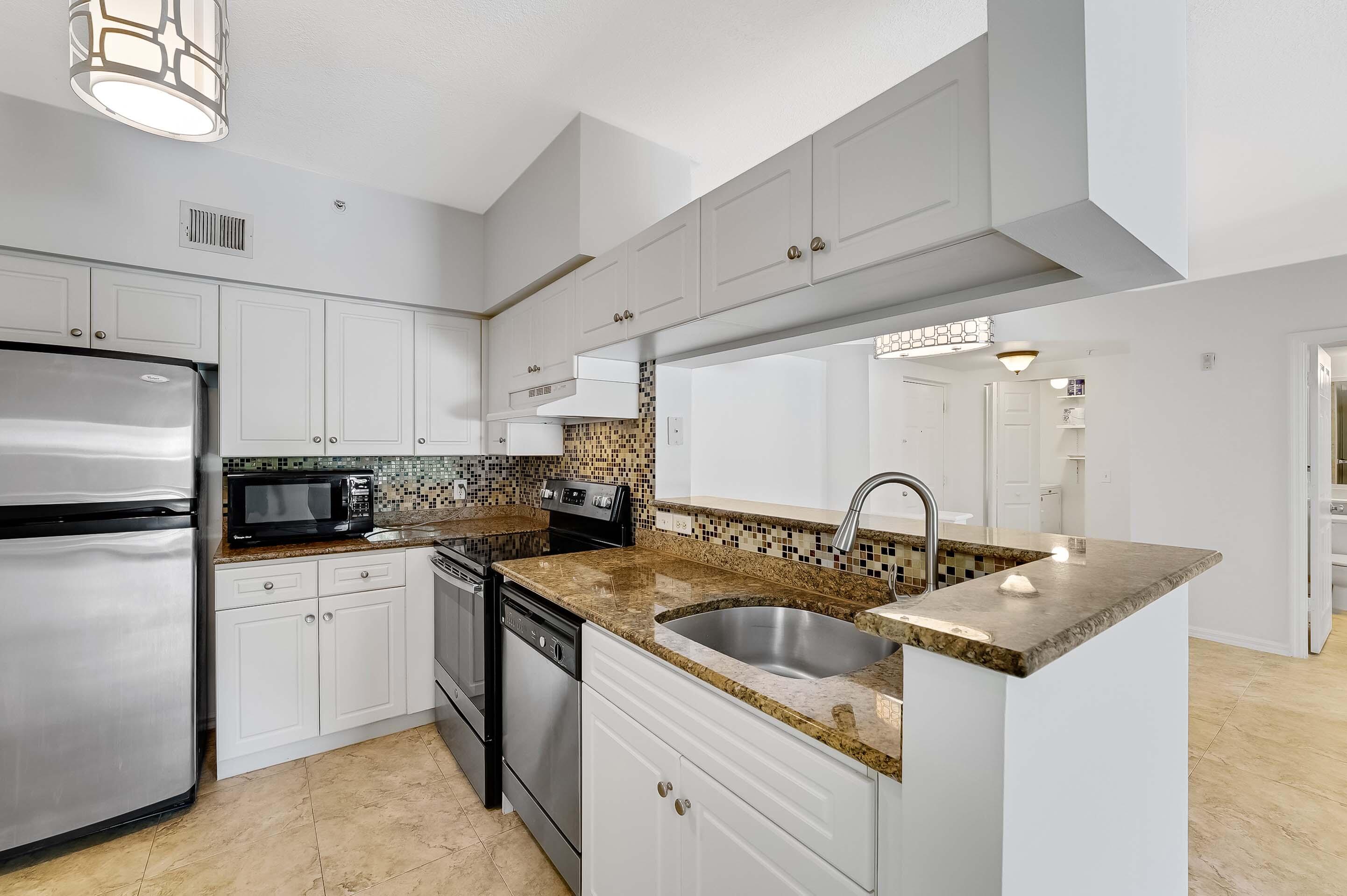 3115 Tuscany Way Boynton Beach, FL 33435 - Photo 21 of 49 a kitchen with granite countertop a sink white cabinets and stainless steel appliances