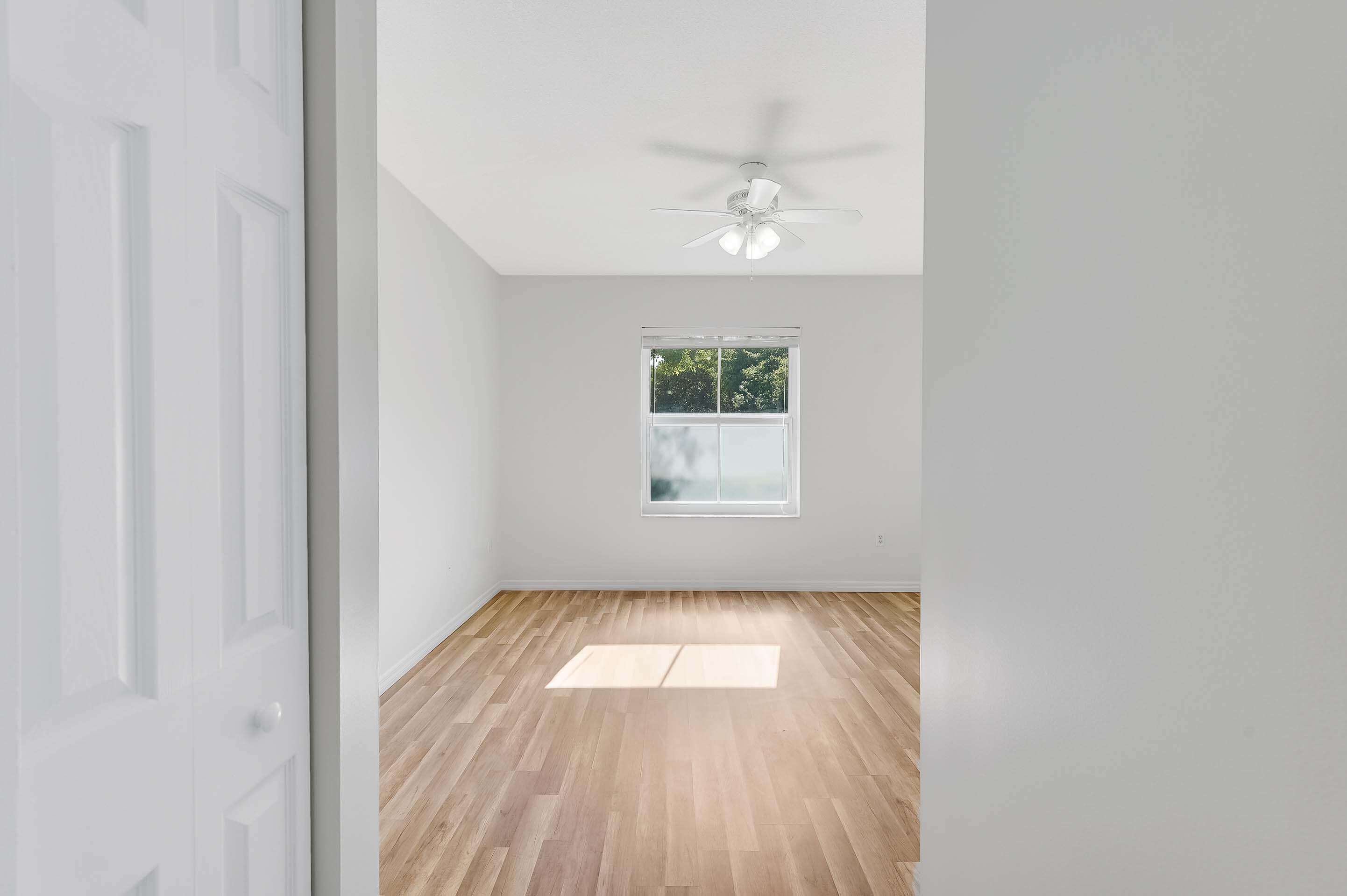 3115 Tuscany Way Boynton Beach, FL 33435 - Photo 34 of 49 an empty room with wooden floor chandelier fan and windows