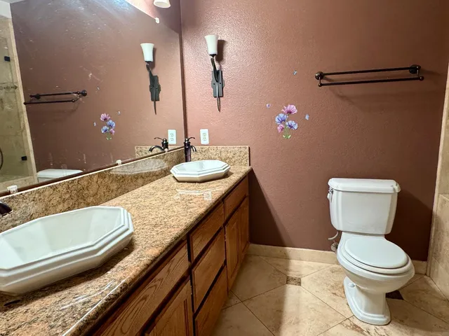 a bathroom with a granite countertop sink a large mirror and toilet