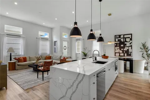 a kitchen with stainless steel appliances kitchen island granite countertop a sink dishwasher a stove a dining table and chairs with wooden floor