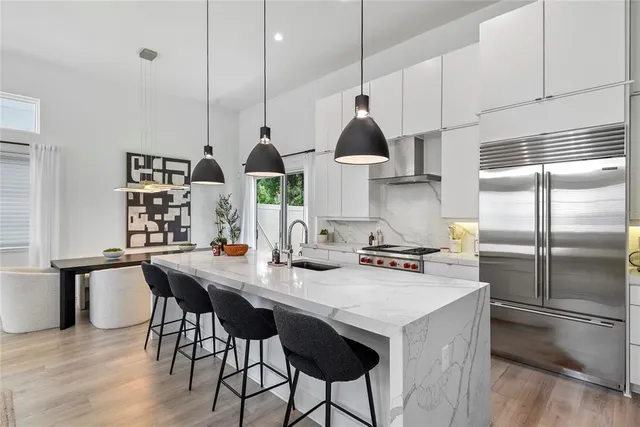 a kitchen with stainless steel appliances a sink a stove a table and chairs