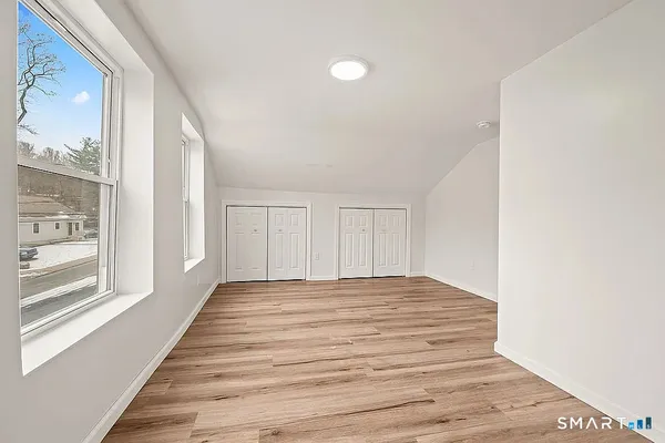 a view of a bedroom with wooden floor and windows
