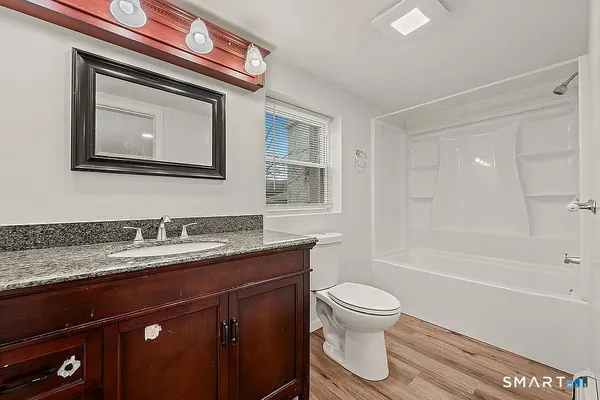 a bathroom with a granite countertop toilet sink and mirror