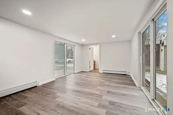 a view of an empty room with wooden floor and a window