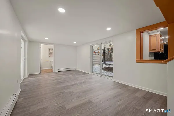a view of an empty room with wooden floor and a window